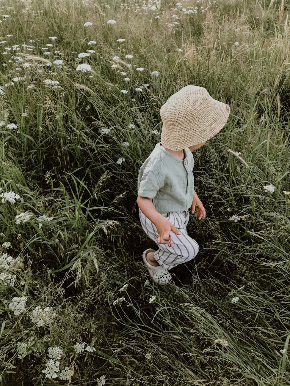 kid in hat walking on grassy field